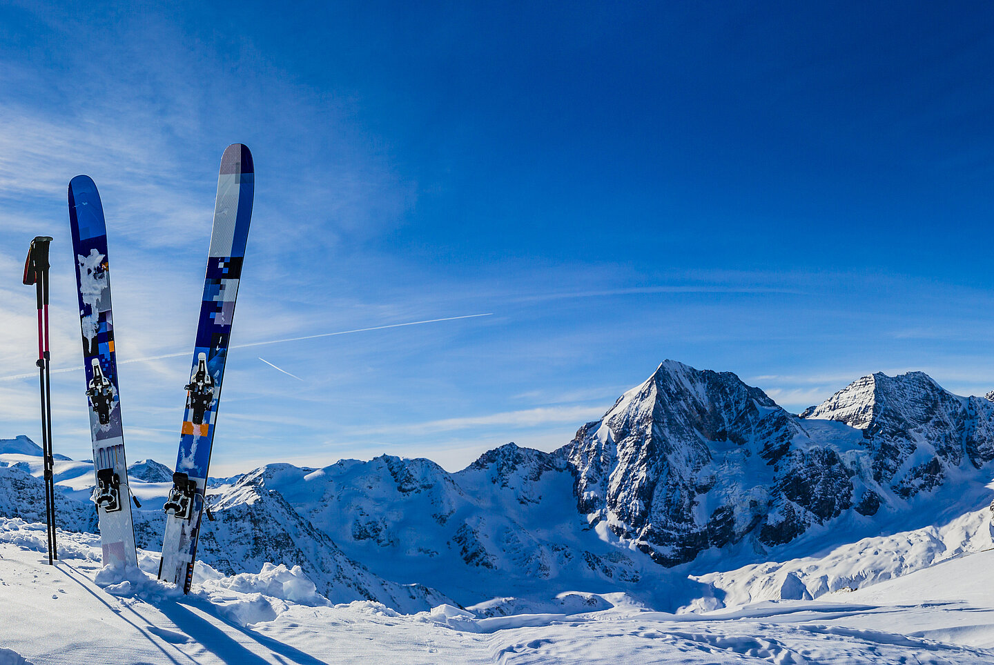 Ein Paar Ski steckt im Schnee auf einer Skipiste