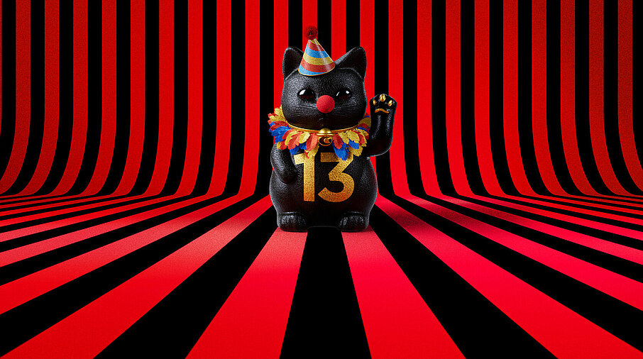 13er Glückskatze mit Faschings-Hut auf rot-schwarz-gestreiftem Hintergrund