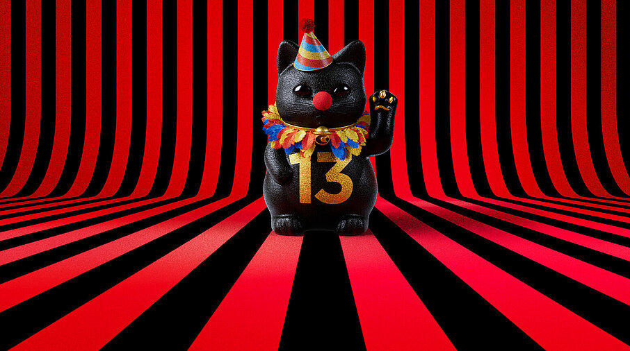 13er Glückskatze mit Faschings-Hut auf rot-schwarz-gestreiftem Hintergrund