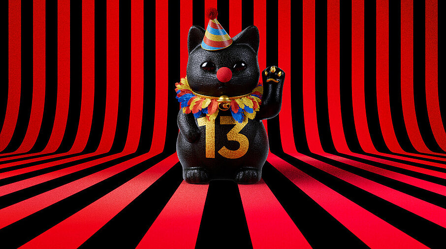 13er Glückskatze mit Faschings-Hut auf rot-schwarz-gestreiftem Hintergrund