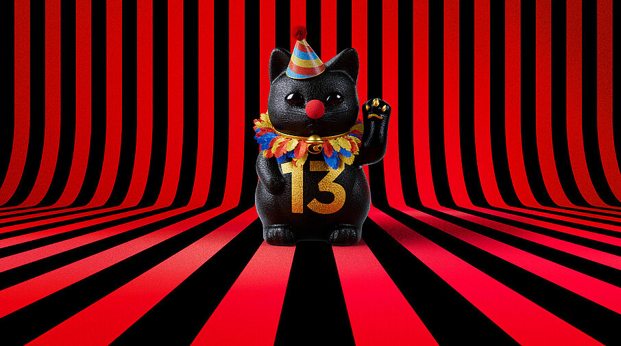 13er Glückskatze mit Faschings-Hut auf rot-schwarz-gestreiftem Hintergrund