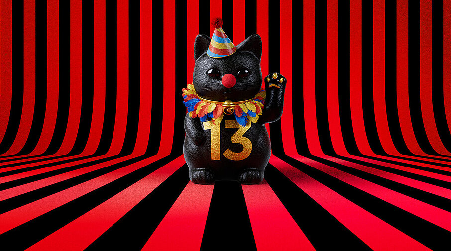 13er Glückskatze mit Faschings-Hut auf rot-schwarz-gestreiftem Hintergrund