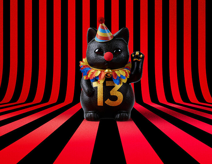 13er Glückskatze mit Faschings-Hut auf rot-schwarz-gestreiftem Hintergrund