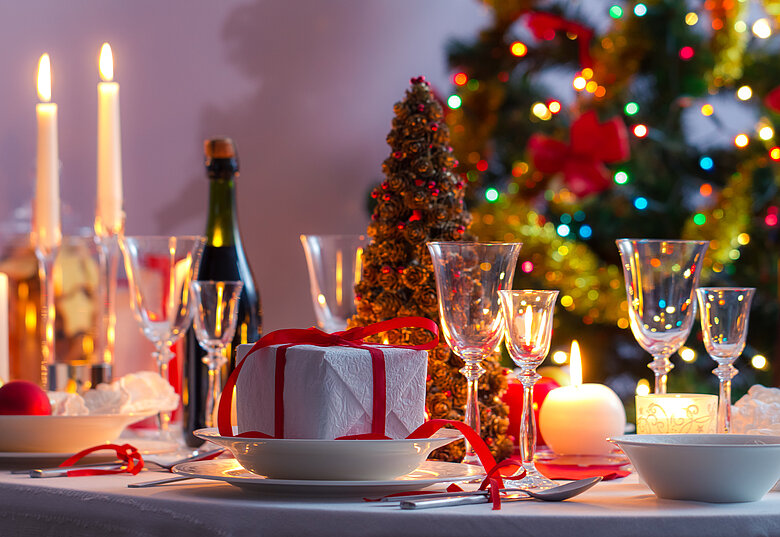 Weihnachtlich gedeckter und dekorierter Tisch mit Geschenken und Kerzen