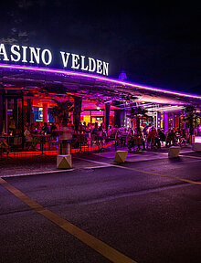 Casino Velden Außenansicht bei Nacht mit violetter Beleuchtung