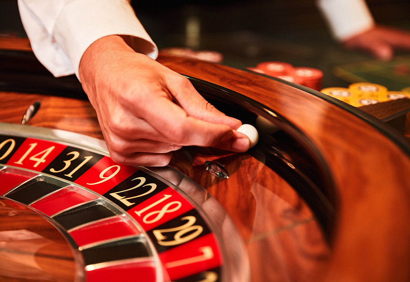 Croupier-Hand im Roulettekessel beim Geben der weißen Roulettekugel
