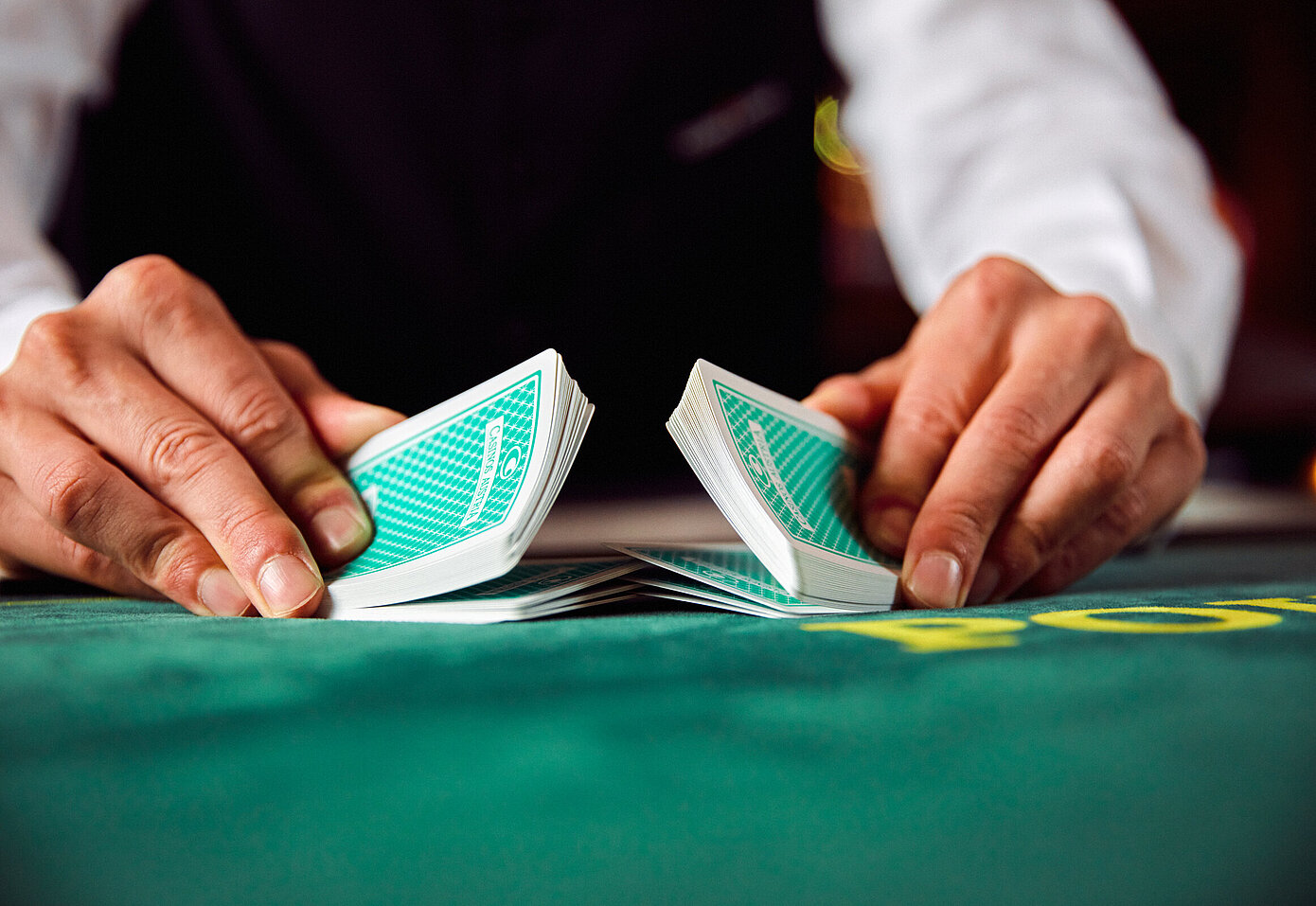 [Translate to English:] Close-up Croupier beim Pokerkarten mischen
