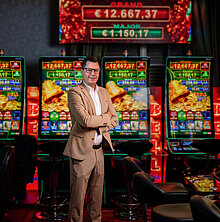 Key Account Manager im Casino Salzburg in hellem Anzug vor Spielautomaten