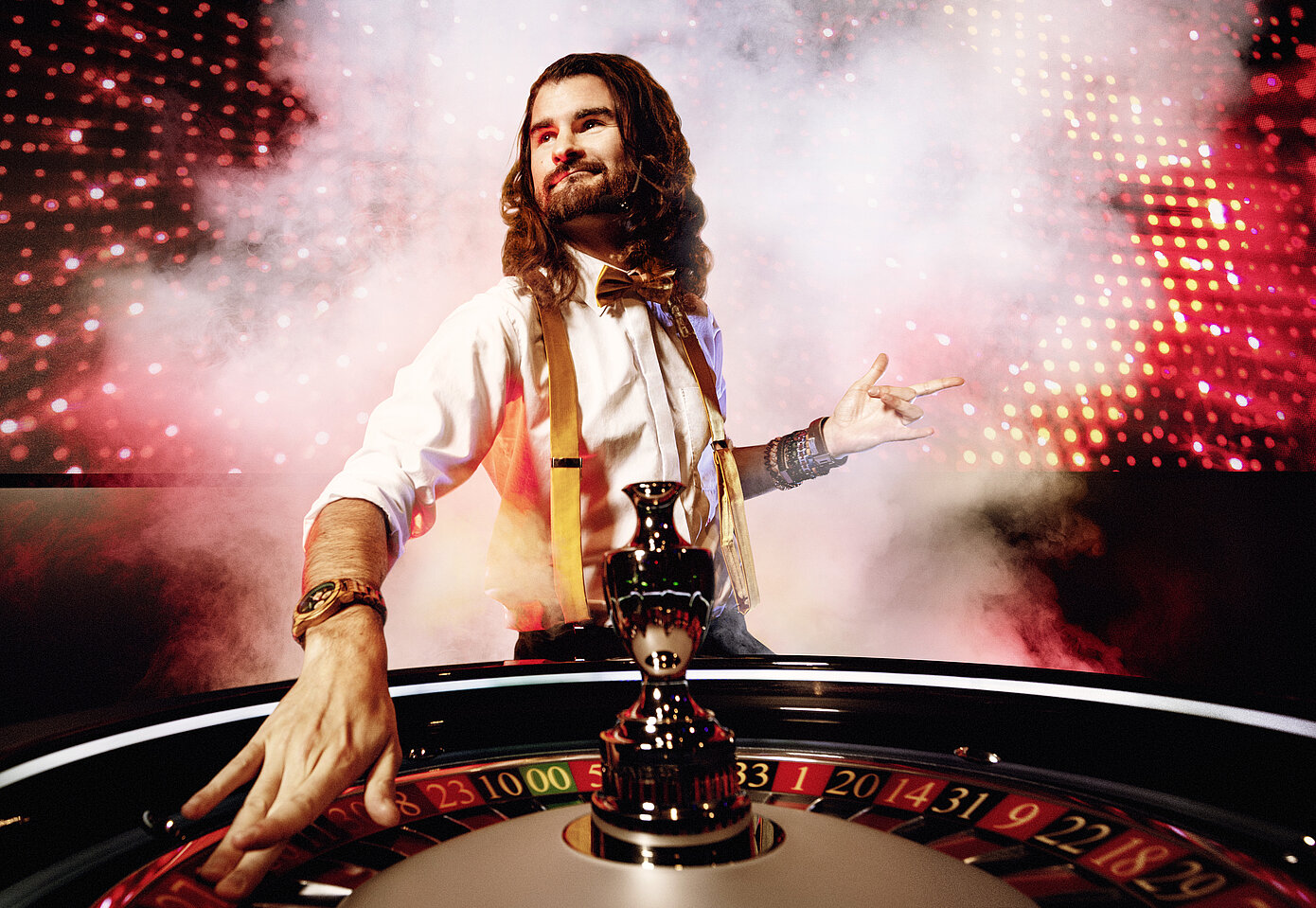 Game Zone Croupier mit Rauch und MEGA LED Wall im Hintergrund und Roulettekessel