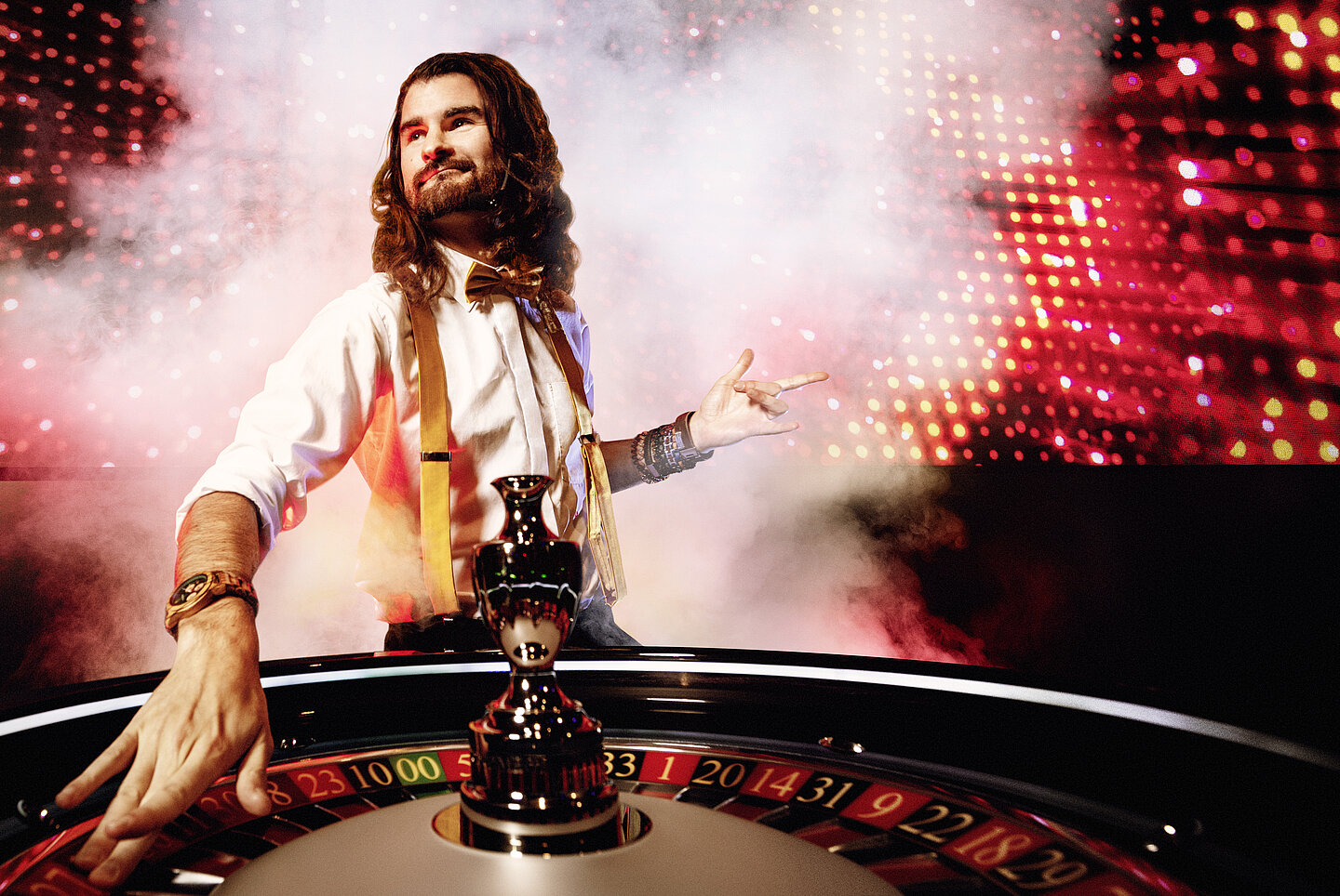 Game Zone Croupier mit Rauch und MEGA LED Wall im Hintergrund und Roulettekessel