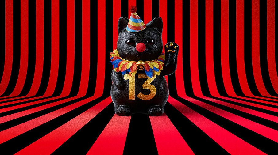 13er Glückskatze mit Faschings-Hut auf rot-schwarz-gestreiftem Hintergrund