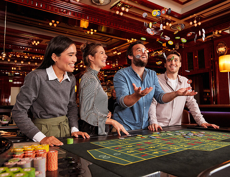 Gruppe beim Roulette-Tisch im Casino Mann wirft Jetons in die Luft