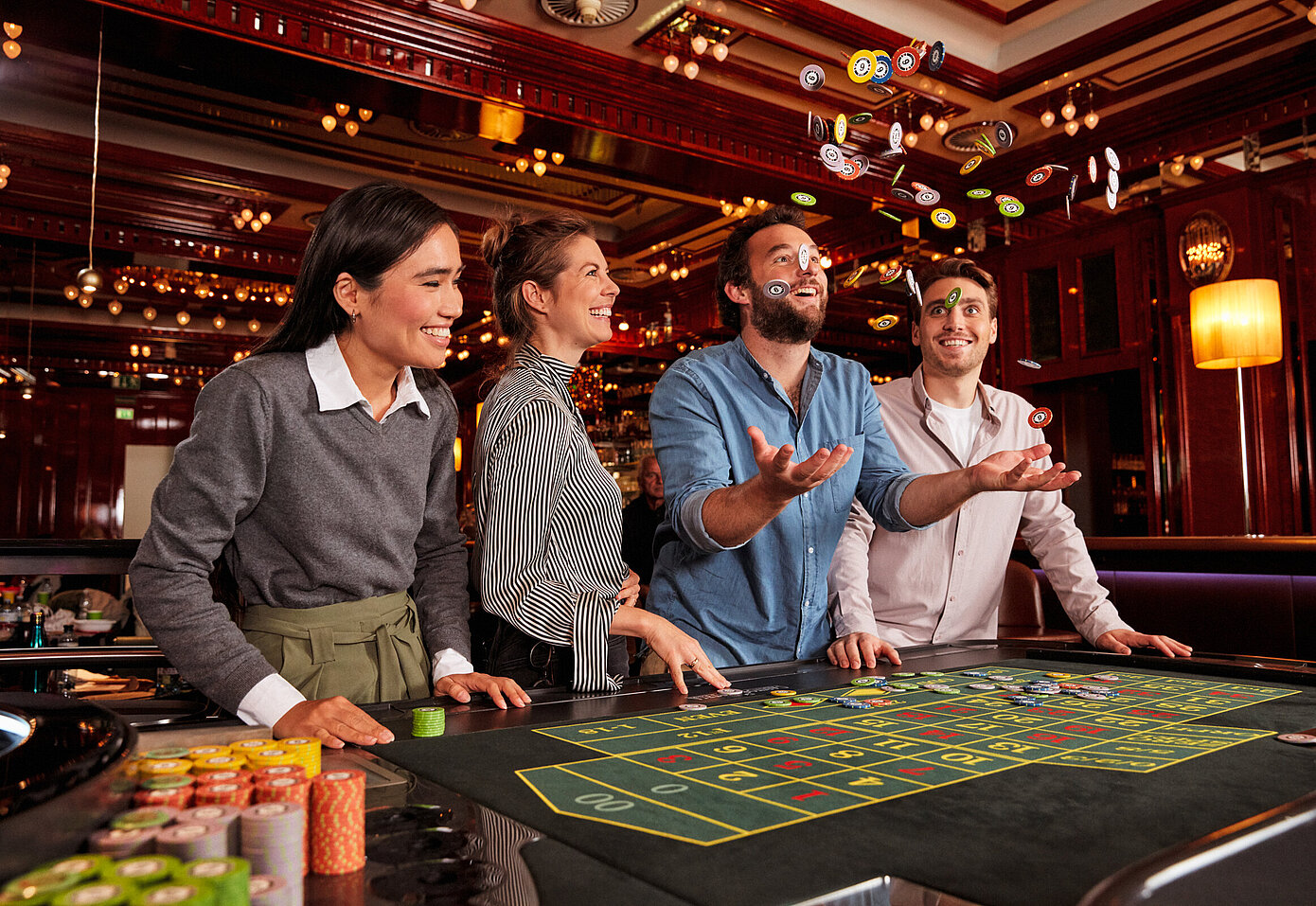 Gruppe beim Roulette-Tisch im Casino Mann wirft Jetons in die Luft
