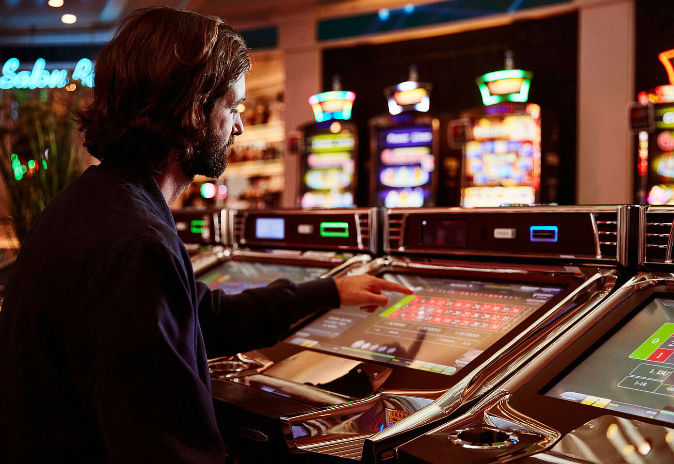 Dunkelhaariger Herr sitzt beim Easy Roulette Automaten im Casino