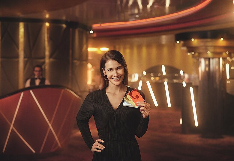Casinos Austria Dame hält Glücks Card in RED GOLD PLATINUM von Casinos Austria in der Hand