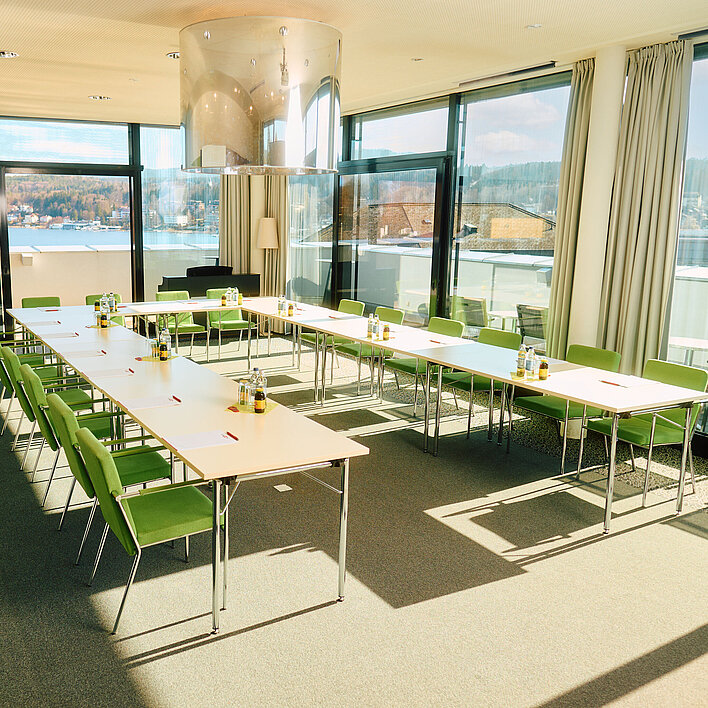 Ein heller Raum mit Tischen in U-Form und Stühlen dazu