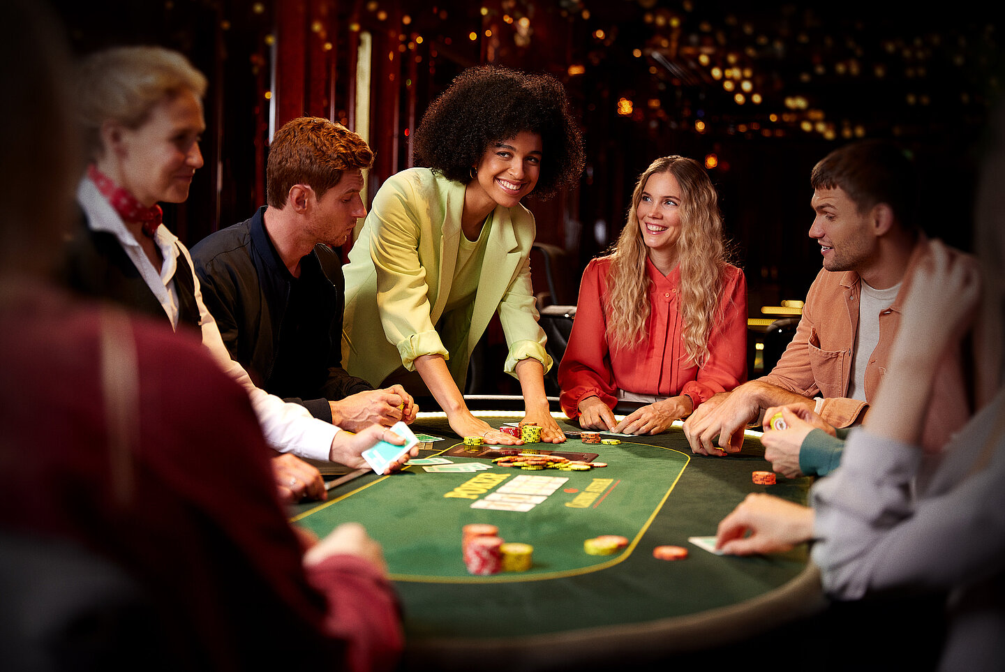 Gruppe Poker Spieler:innen am Poker Tisch mit Jetons und Karten