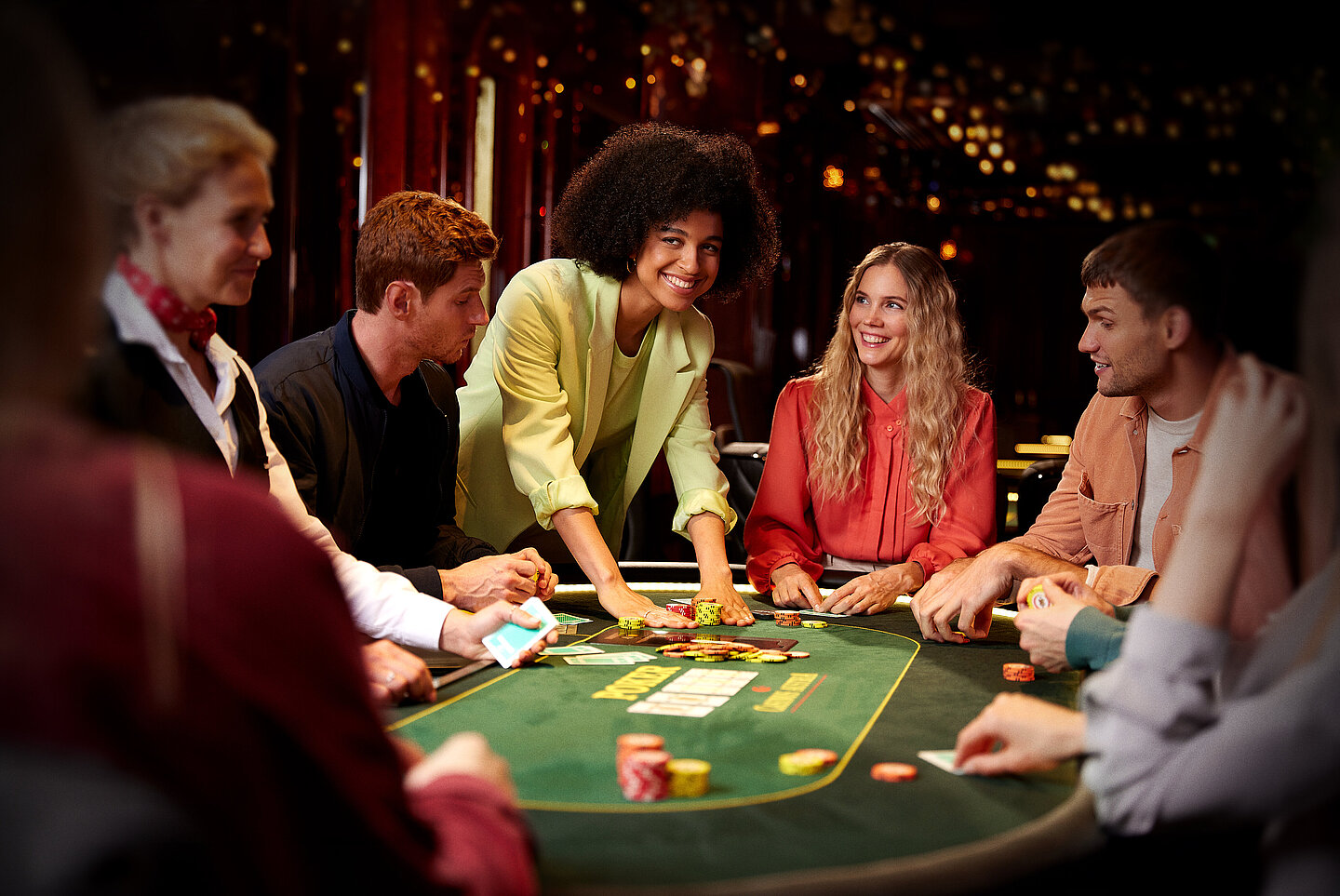 Gruppe Poker Spieler:innen am Poker Tisch mit Jetons und Karten