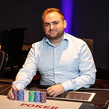 xPokermanager im Casino Linz, Thomas Wegenschimmel, sitzt an einem Pokertisch und lächelt in die Kamera.