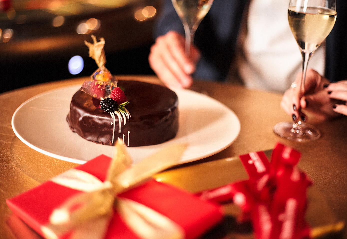 Tisch mit Schokoladen-Geburtstagstorte und rotem Geschenkpaket